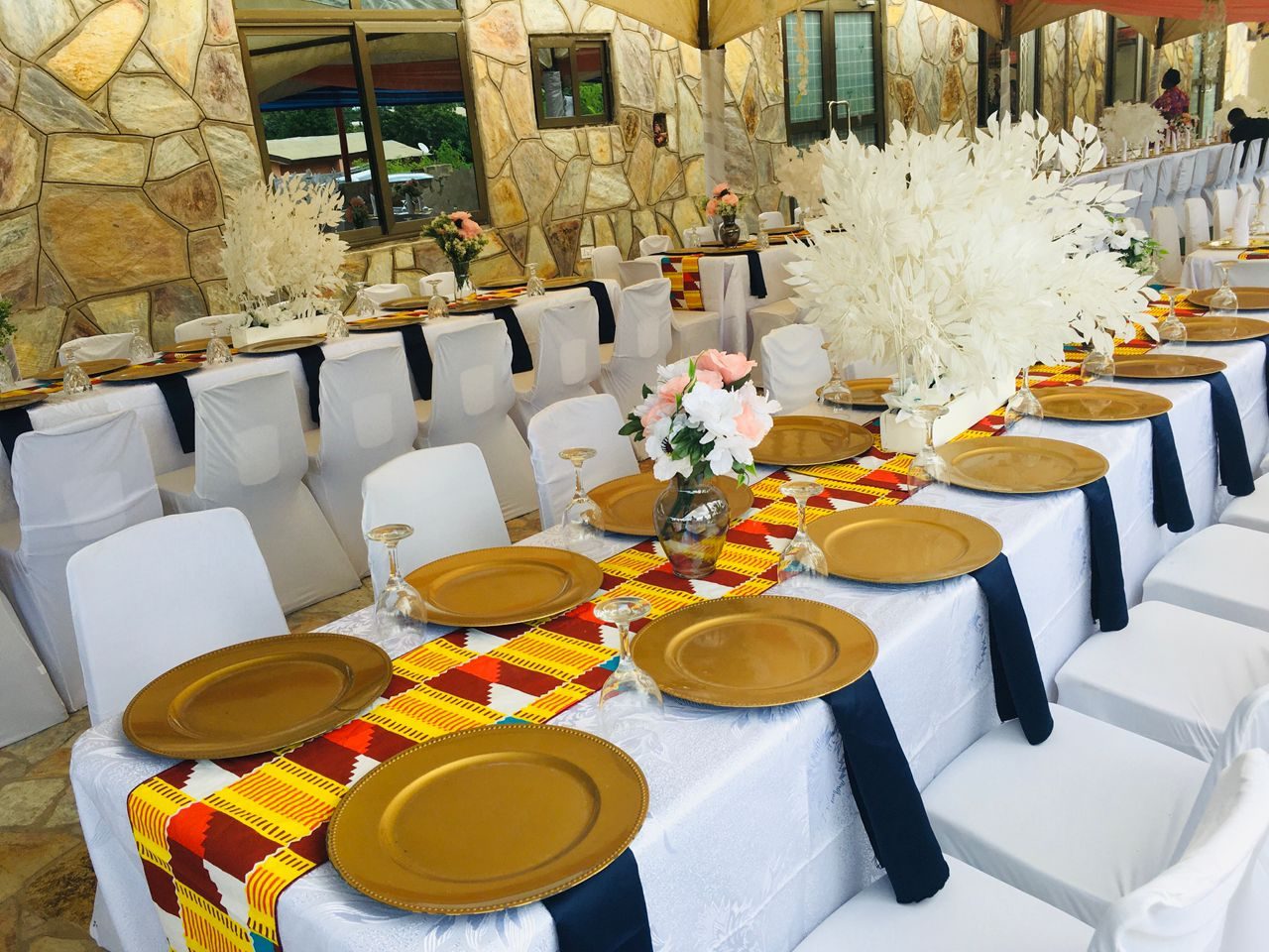 Outdoor event table set with Ghanaian print runners and gold place settings